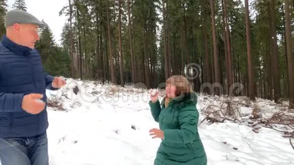一个穿着夹克的中年男子冬天在一片白雪皑皑的森林里用大的单反相机拍照爱好概念视频的预览图