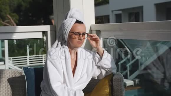 一位中年妇女躺在露台上的阳光休息室里洗了个热水澡后在新鲜空气中休息视频的预览图