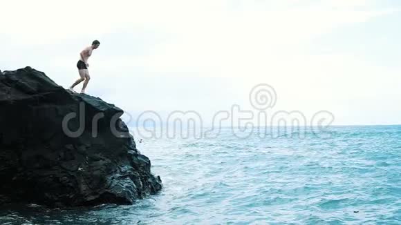 一个年轻人从悬崖上跳进蓝色的大海活跃有趣的暑假视频的预览图