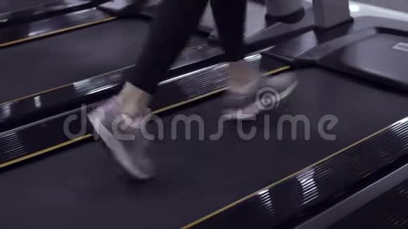 在健身房跑步机上运动的女人的运动鞋上观看视频的预览图