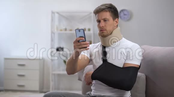 男性手臂吊带和泡沫颈项圈滚动智能手机康复期视频的预览图