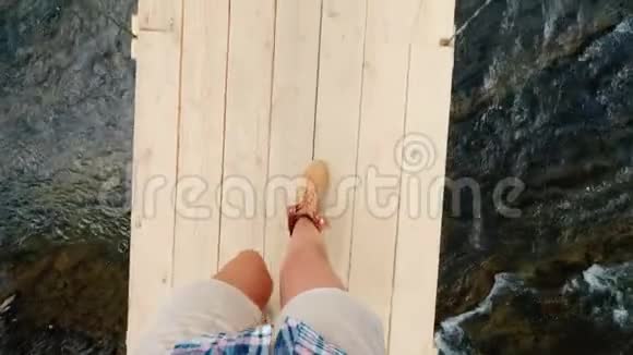 一个女人走在一座摇摇晃晃的木桥上穿过一条山河第一人称观点视频的预览图