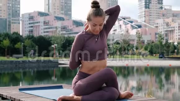 年轻女子做瑜伽运动与城市背景Gomukhasana视频的预览图