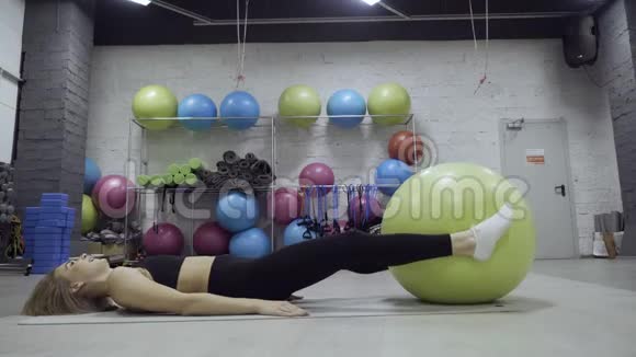 运动的女人在健身房里用绿色健身球做运动视频的预览图
