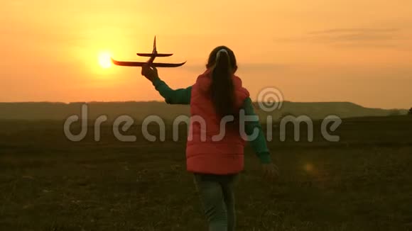 快乐的女孩带着玩具飞机在日落的背景下跑过田野幸福家庭的概念一个孩子视频的预览图