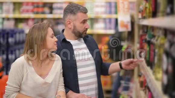 美丽的年轻夫妇在超市度过时光家庭有很多乐趣从超市挑选葡萄酒视频的预览图