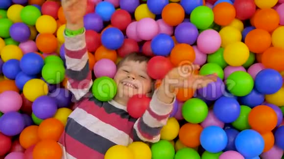 娱乐概念现代生活背景男孩躺在游泳池里手里拿着五颜六色的软球视频的预览图
