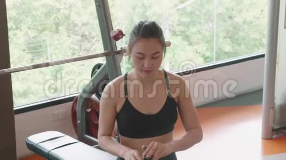 有魅力的亚洲女孩在健身运动健身房从瓶子里喝水享受淡水的年轻妇女的特写视频的预览图