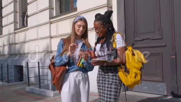 正面观两位非洲裔和欧裔美学生站在一起女人一起学习视频的预览图