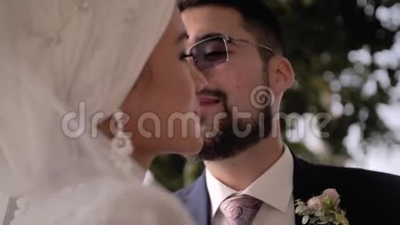 一个戴着眼镜和胡子的家伙轻轻地亲吻他的女朋友的脸颊一对非常漂亮的年轻夫妇视频的预览图