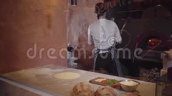 熟练的披萨制造商正在玻璃后面的现代餐厅厨房做面团穿着厨师制服的年轻人视频的预览图