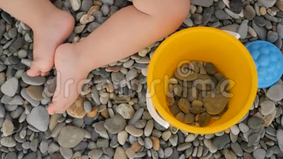 小女孩用玩具在鹅卵石海滩上的腿特写视频的预览图