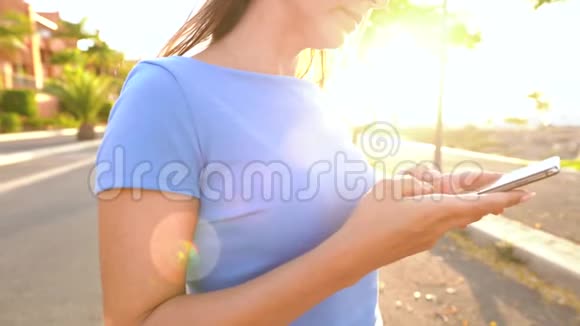 日落时分女人在棕榈街使用智能手机视频的预览图