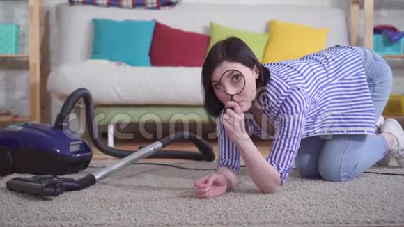 客厅里的年轻女子用放大镜检查地毯视频的预览图