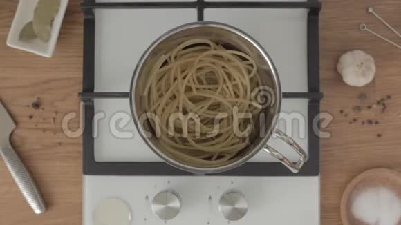 将煮好的意大利面和油混合在厨房的炉子上的金属锅中视频的预览图