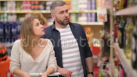 美丽的年轻夫妇在超市度过时光家庭有很多乐趣从超市挑选葡萄酒视频的预览图