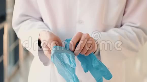 穿长袍的医生正戴着蓝色的医用手套视频的预览图