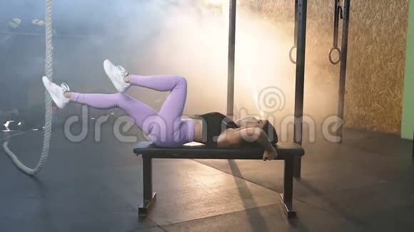 年轻女子在健身房的长凳上集中训练腿视频的预览图