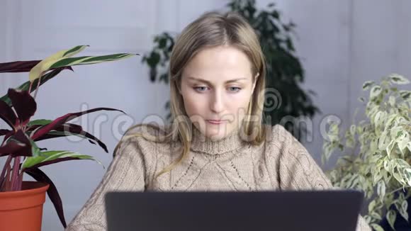 穿着家居服的年轻女子坐在笔记本电脑后面竖起大拇指视频的预览图