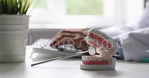 牙医在牙科诊所工作办公室打字电脑键盘重点是牙齿模型视频的预览图