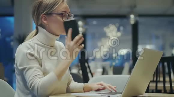 年轻女子坐在咖啡馆里用手机接电话视频的预览图