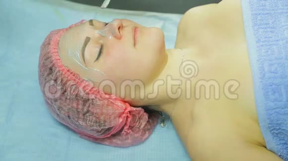 戴手套的美容师用刷子在女人脸上涂一个泥面膜视频的预览图