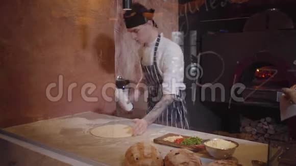 熟练的披萨制造商正在玻璃后面的现代餐厅厨房做面团他把牛奶倒在表格上视频的预览图