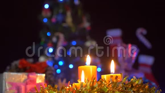 背景中有一棵装饰好的圣诞树的美丽燃烧的蜡烛视频的预览图