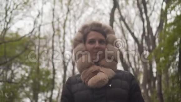 一个穿着暖和的黑色夹克的女孩穿过树林女孩跟随相机从上到下拍摄视频的预览图