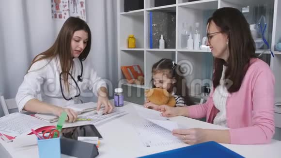 孩子们医生给一个小女孩开维他命药她和她的母亲一起来到一家诊所的接待处视频的预览图