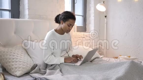 背疼的年轻非洲女孩在床上工作视频的预览图