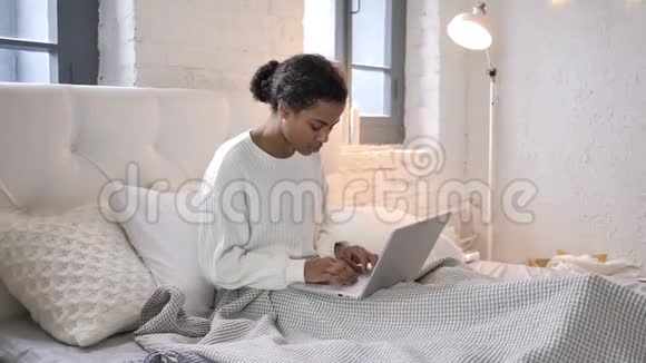 震惊的年轻非洲女孩想在床上笔记本电脑的结果视频的预览图
