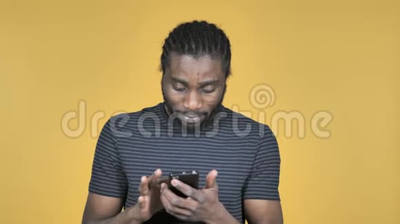 黄色背景下使用智能手机休克的非洲男子视频的预览图