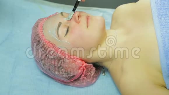 戴手套的美容师在女人的脸上戴上化妆面具侧视图视频的预览图