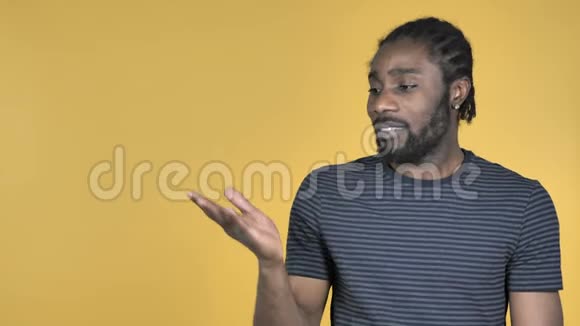 休闲非洲男子展示产品在侧面黄色背景视频的预览图
