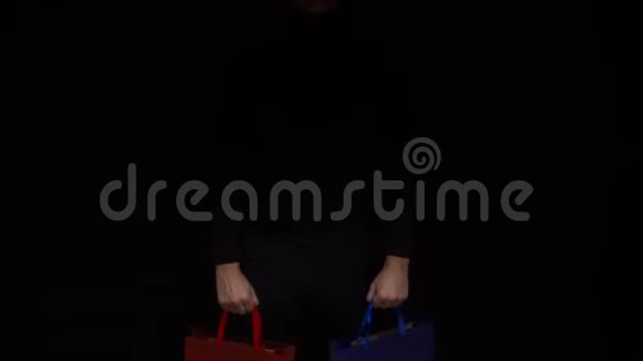 梅手拿着一个五颜六色的包裹在黑色的背景上复制空间视频的预览图