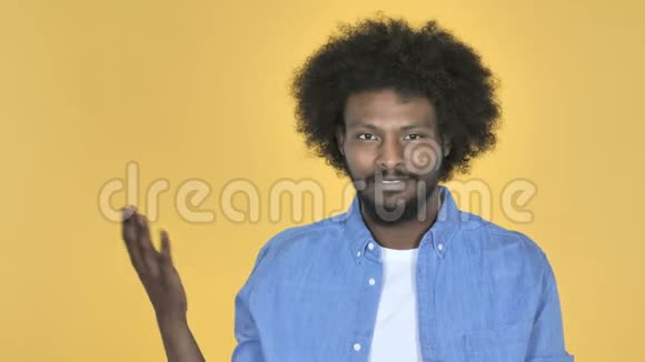 非洲裔美国人在侧面展示产品黄色背景视频的预览图