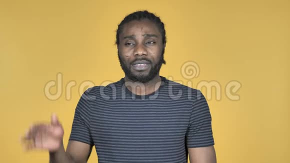 非洲男子听力秘密站在黄色背景下视频的预览图