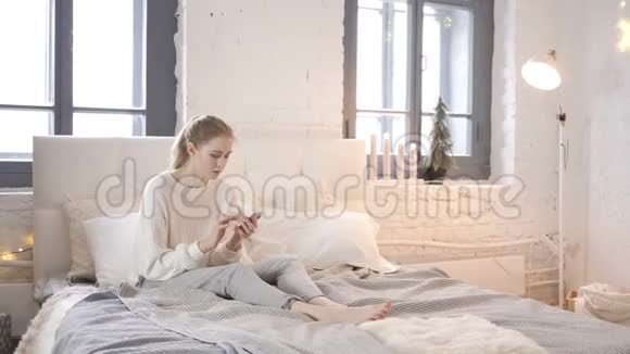 小女孩在床上使用智能手机视频的预览图