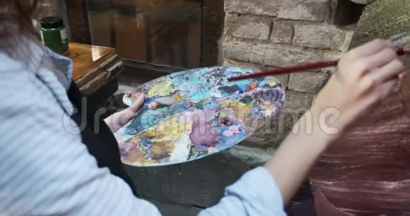 在木调色板上用女性手混合油彩有魅力的女孩创造了现代艺术绘画接近女性视频的预览图