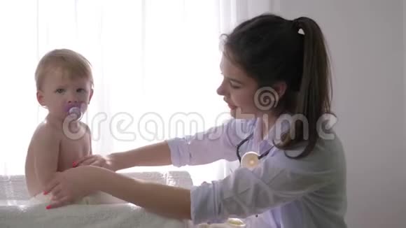 小孩子在医生的体检中专业的儿科医生女人在明亮的自然中检查可爱的男孩视频的预览图