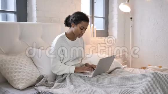 坐在床上工作的非洲少女视频的预览图