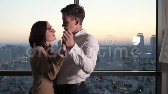 一对夫妇男人和女人在全景窗口附近跳舞可以看到城市的景色视频的预览图