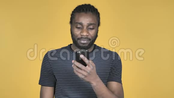 黄色背景下的非洲男子浏览器智能手机视频的预览图