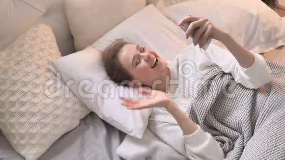 躺在床上的少女在线视频聊天的俯视图视频的预览图