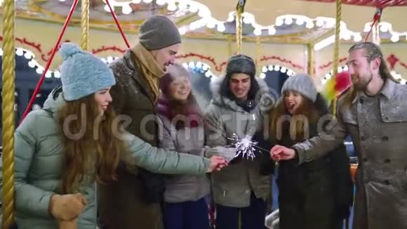 微笑的朋友在圣诞节市场上玩旋转木马的火花新年快乐的男人和女人视频的预览图
