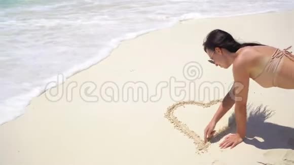 沙滩上的年轻女子在白沙上画画视频的预览图