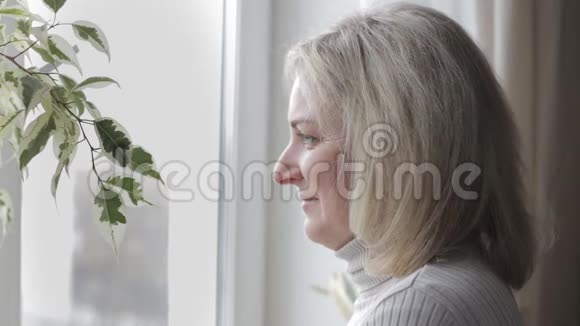 女人望着窗外把脸转向照相机视频的预览图
