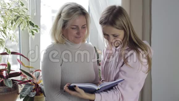 母女俩看着一本有笔记和谈话的笔记本视频的预览图