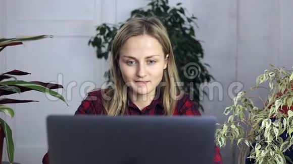 年轻女子在家里买笔记本电脑周围有很多室内植物视频的预览图